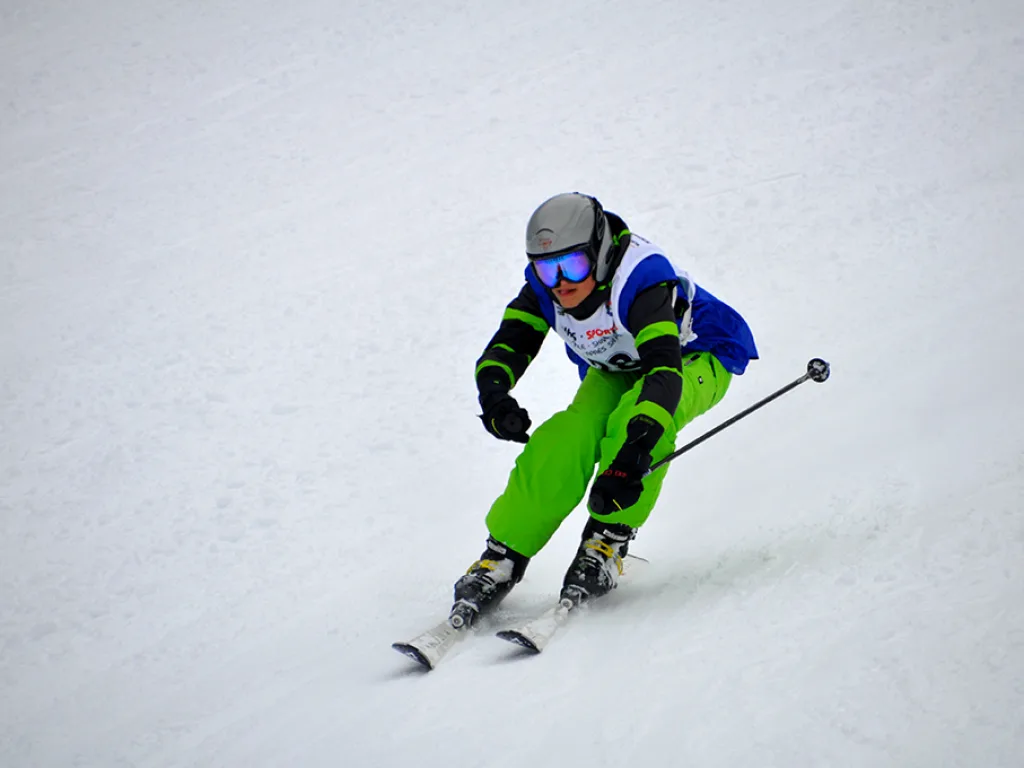 Skifahrer in grüner Hose in tiefer Hocke.